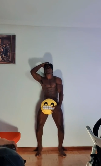 Jordan Jameson posing in his apartment holding smiling emoji pillow over his crotch