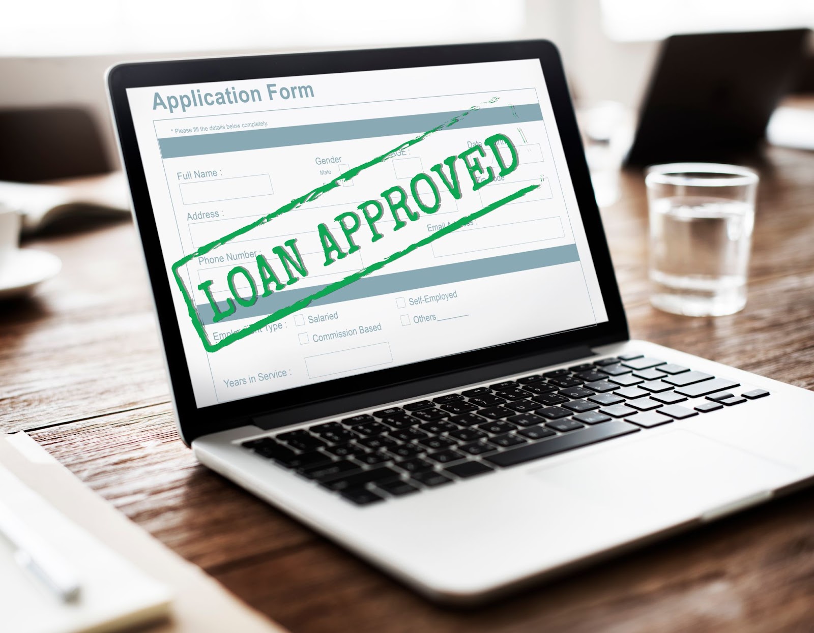 A laptop screen displaying a message confirming the approval of a loan.