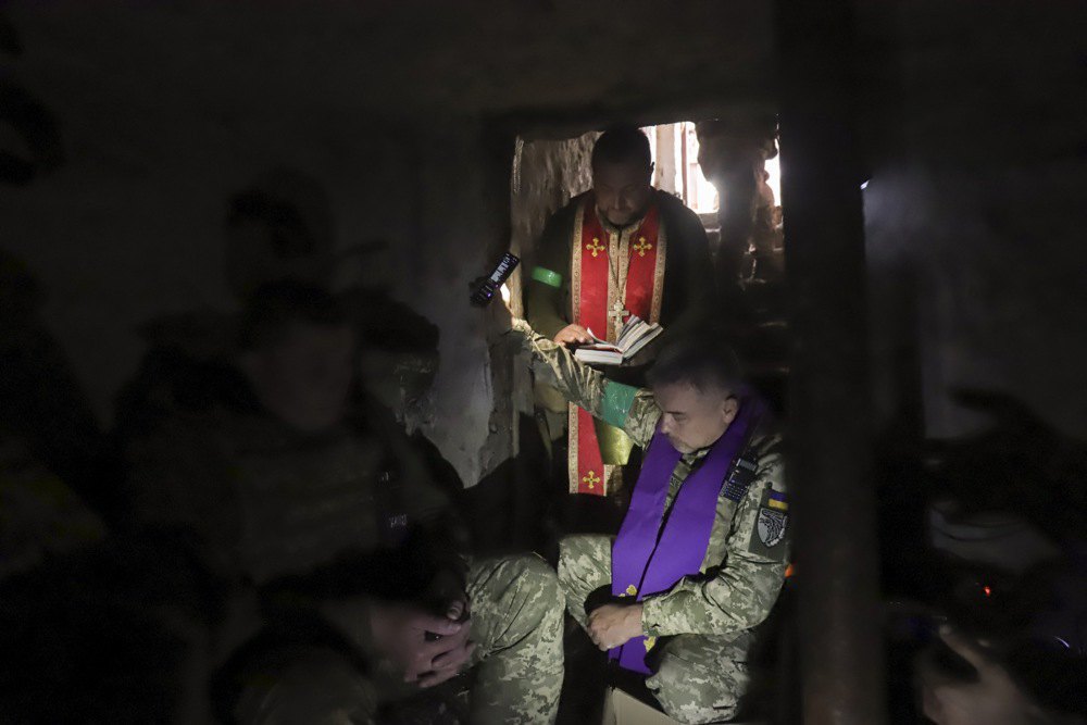 Військовий капелан молиться разом з українськими воїнами в укритті на їхніх позиціях у селі неподалік міста Ізюм Харківської області, Україна, 24 квітня 2022 р.
