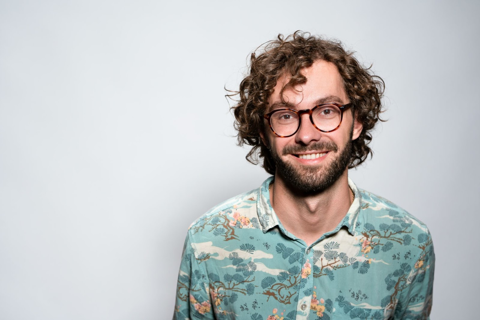 A guy is smiling warmly and carrying his spectacles nicely with a subtle pose for his business headshots.