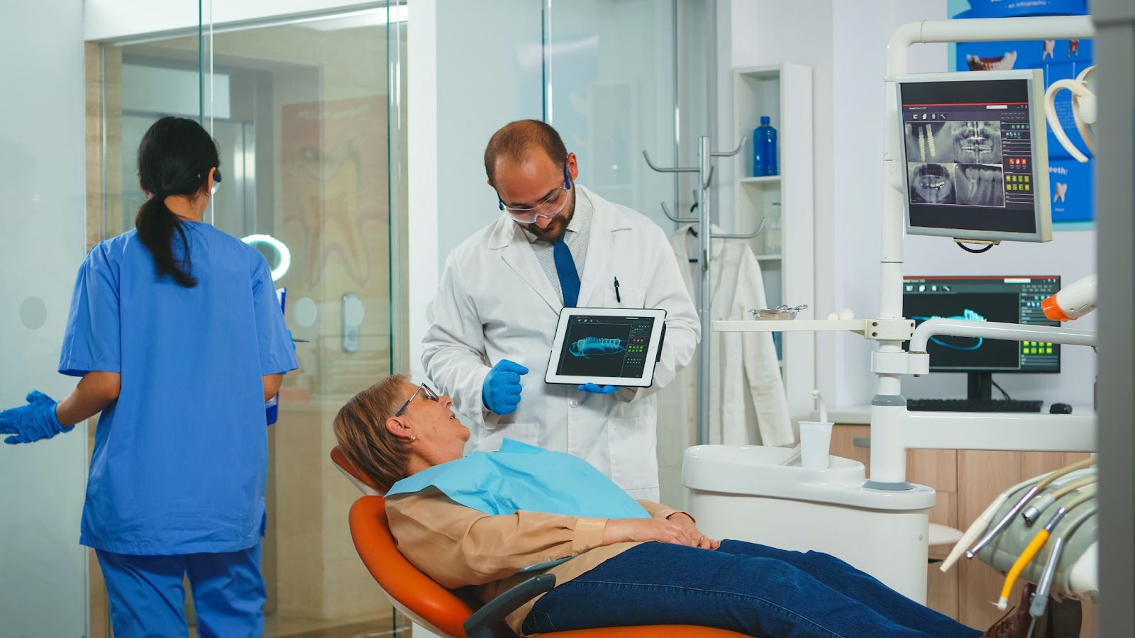  Dentistry doctor showing an x-ray of teeth to the patient using a tablet in a dental clinic.