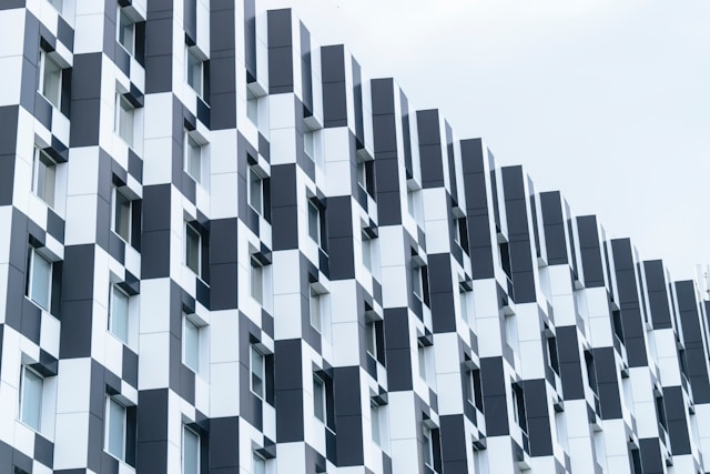 A grey building with a lot of windows projecting out and a clear blue sky in the background