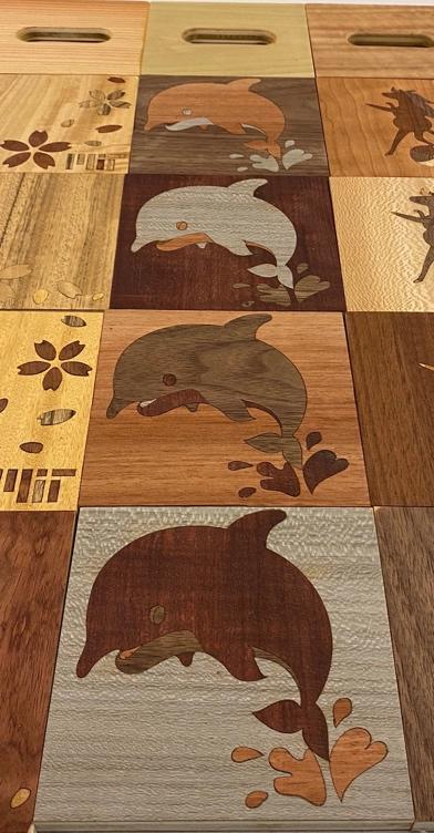 The wood blocks lined up, each one featuring the leaping dolphin colored with a different wood stain.