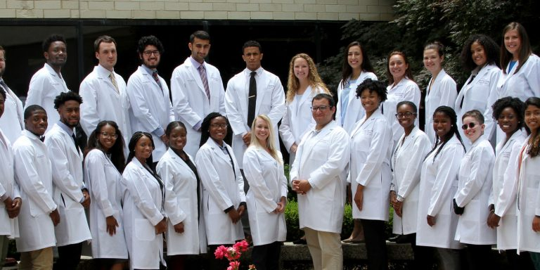 A group of medical students and professors at Brody School of Medicine, posing for a photo in a large common area. 