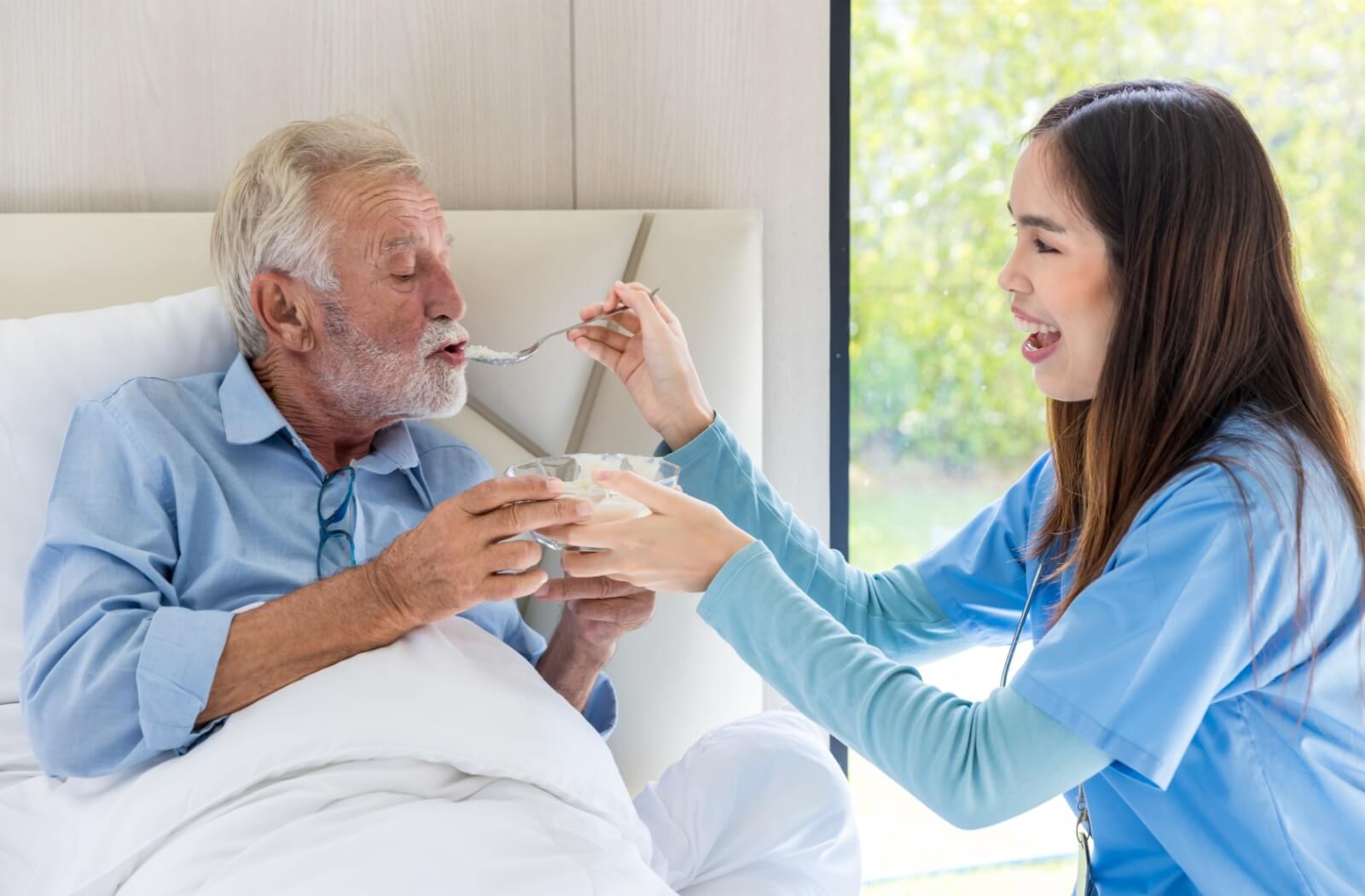 A personal care home staff feeding a resident.