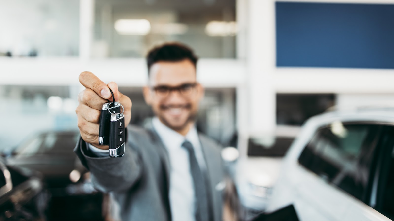 A sales agent handing a set of car keys to the new owner