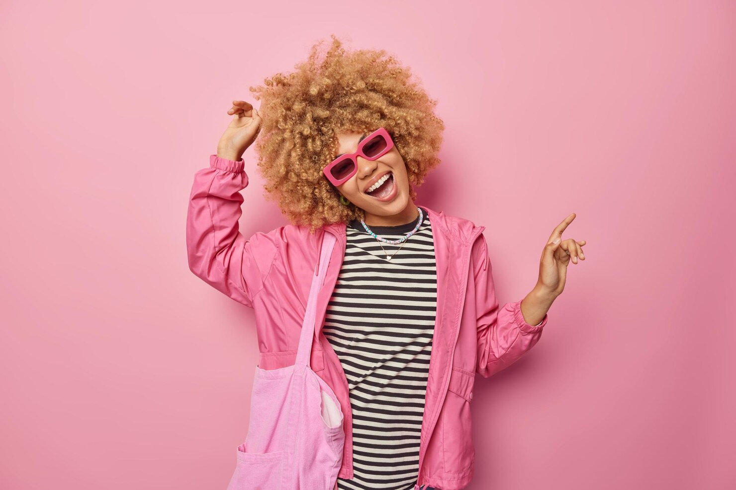 A girl laughing wearing pink jacket and glasses.