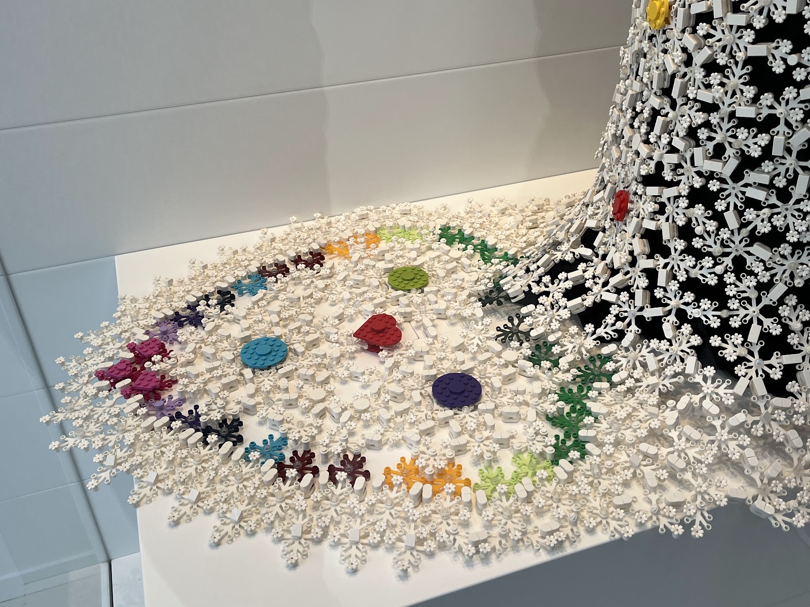 A photo of a white and colorful wedding dress train, on display in the Masterpiece Gallery, made from LEGO parts, especially LEGO leaf elements