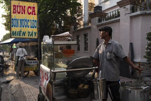 Pham Van Sang, a food vendor who migrated from the Mekong Delta, prepares a noodle dish at his food stall in Ho Chi Minh City, Vietnam, Monday, Jan. 22, 2024. He sells noodles in the city's industrial zone, a destination for many migrants from the Mekong Delta seeking a better life. (AP Photo/Jae C. Hong)