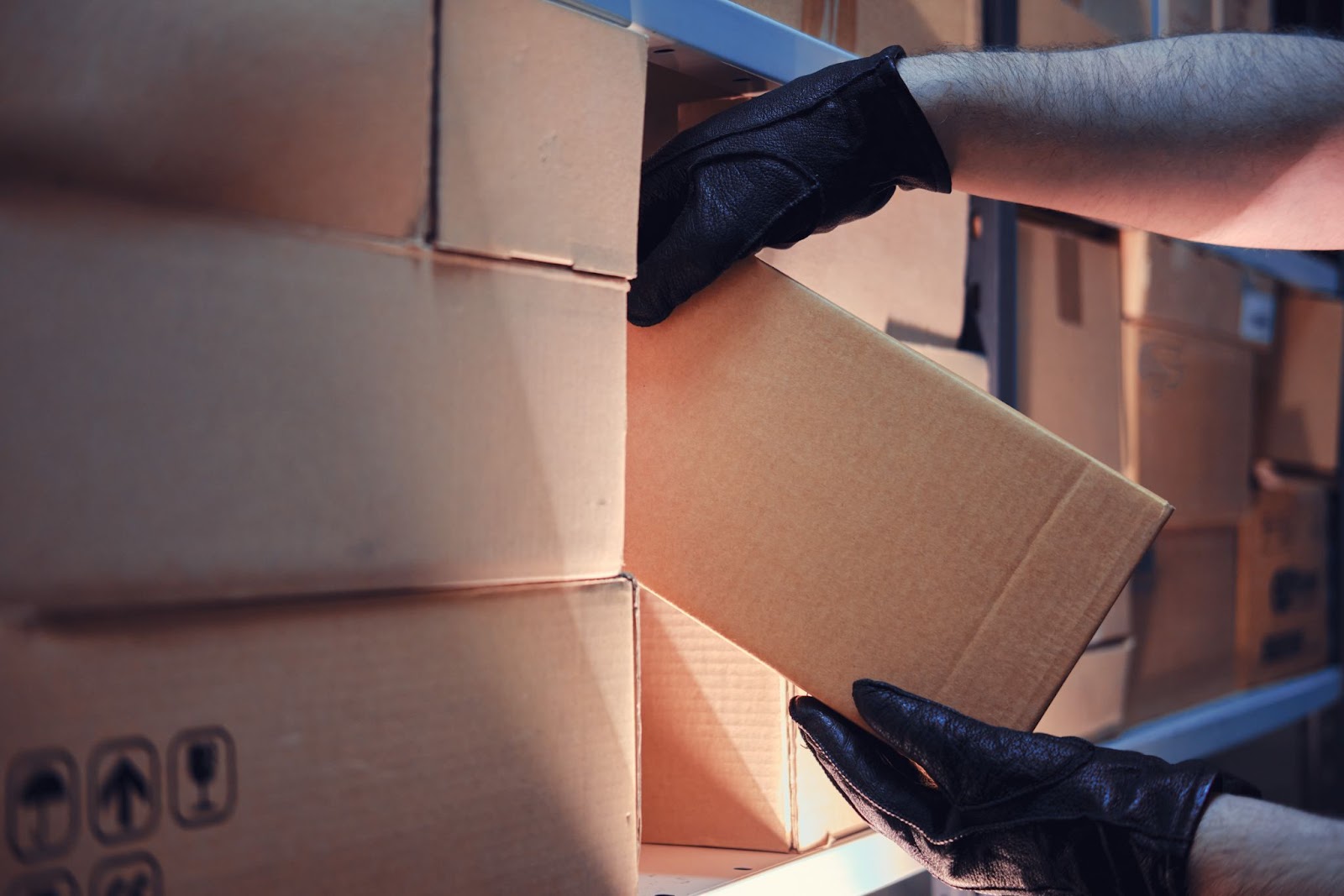 Hands placing a box on a warehouse shelf.