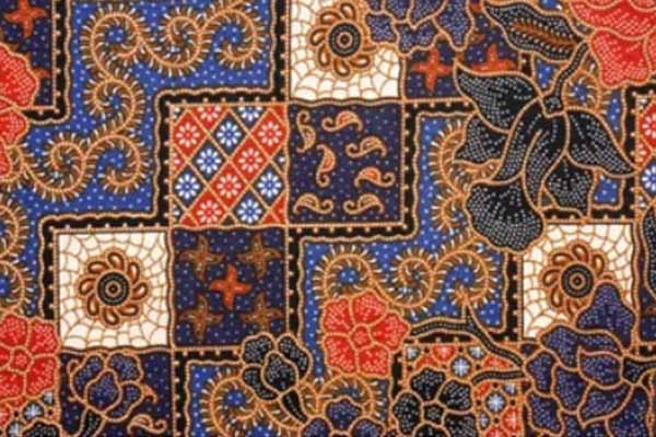 A detailed batik fabric pattern featuring intricate designs and a vibrant mosaic of red, blue, and gold colours.