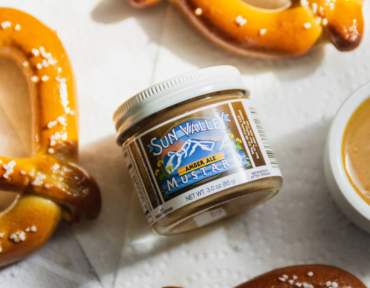 jar of mustard surrounded by soft pretzels and a ramekin with dipping mustard
