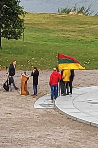 A group of people standing outside with a flag

Description automatically generated