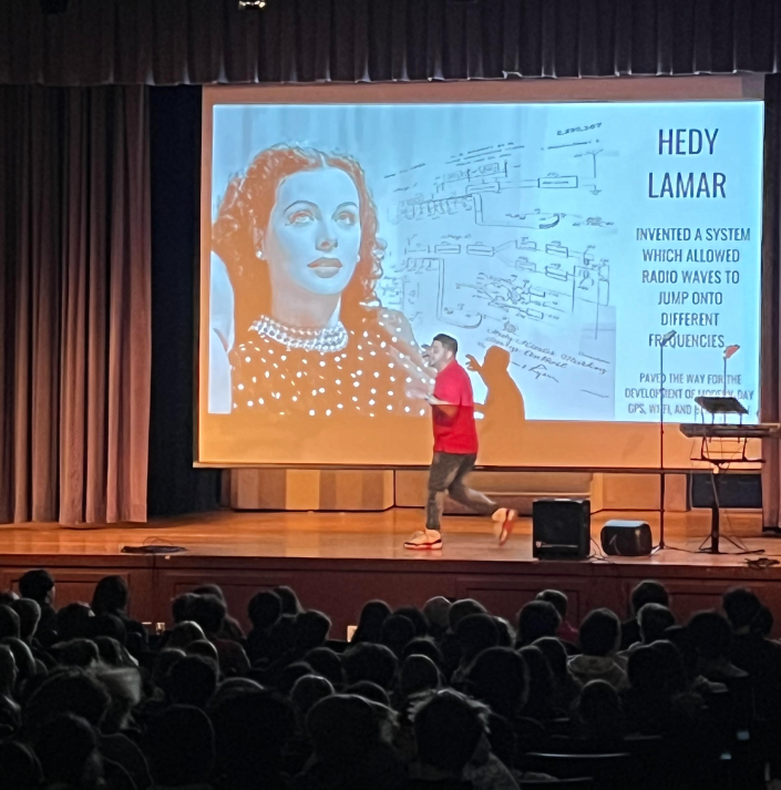 the STEAM the Streets presenter on stage with a slide show of Hedy Lamar