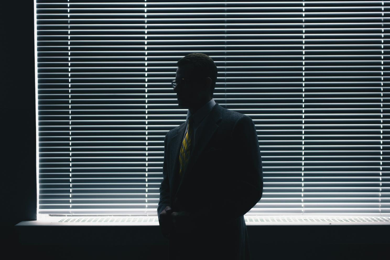 A man standing against a window with blinds. Selecting the right entrepreneur motivational speakers for your event is critical to achieving your event's objectives and leaving a lasting impact on your audience.