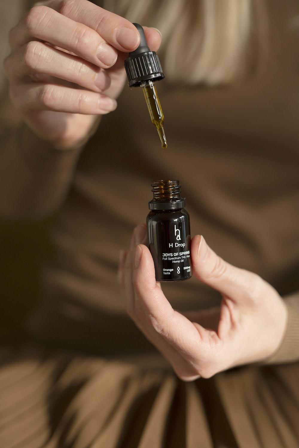 a woman holding a small bottle of essential oils