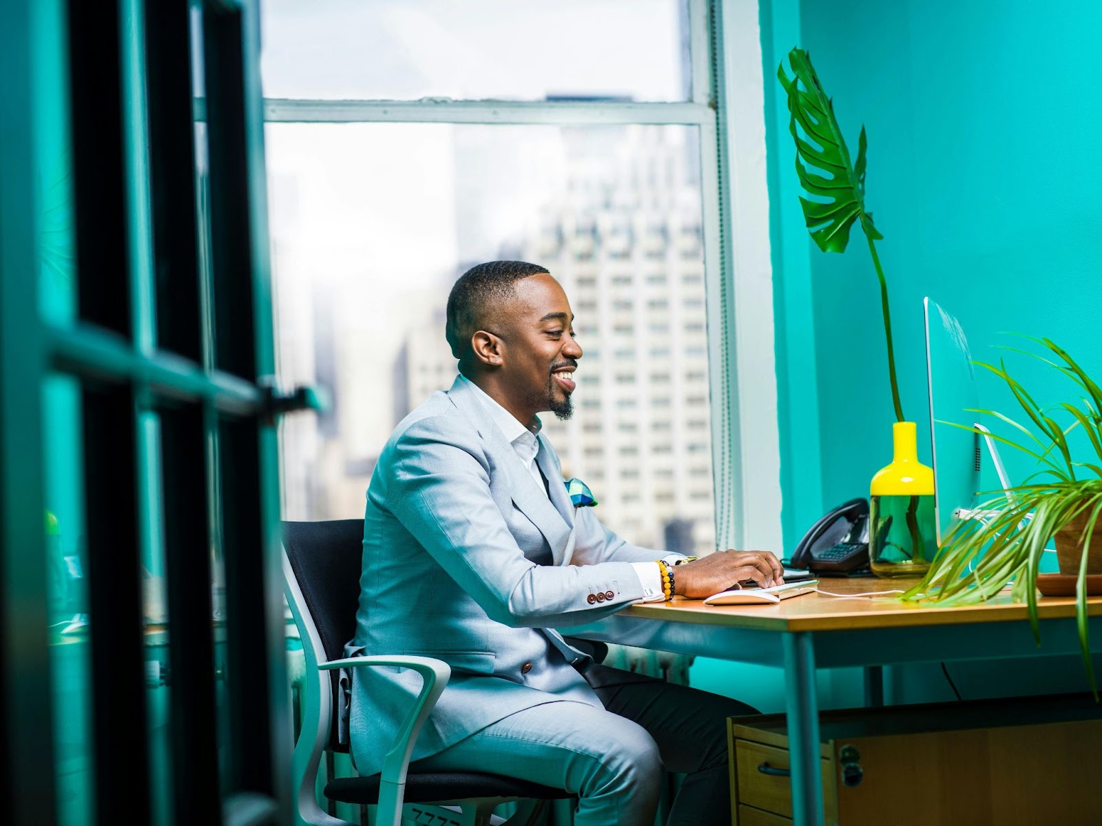 A young african american man sitting at a desk with a blue business suit starting his job search and path to success.