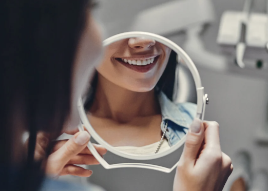 Person looking at their smile in a hand mirror