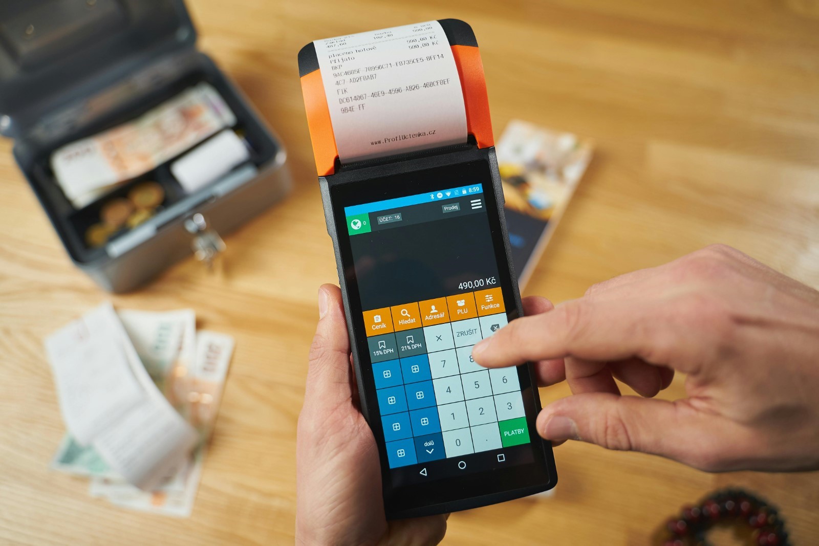 Student making a payment on a credit card machine, cash notes in the background.