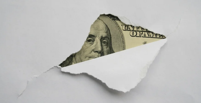 A paper bill sticking out of a hole in a white paper Description automatically generated
