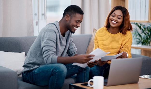 Home smile and black couple with paperwork laptop and discussion with budget conversation and planning funding partnership man and woman with technology talking and documents for investments