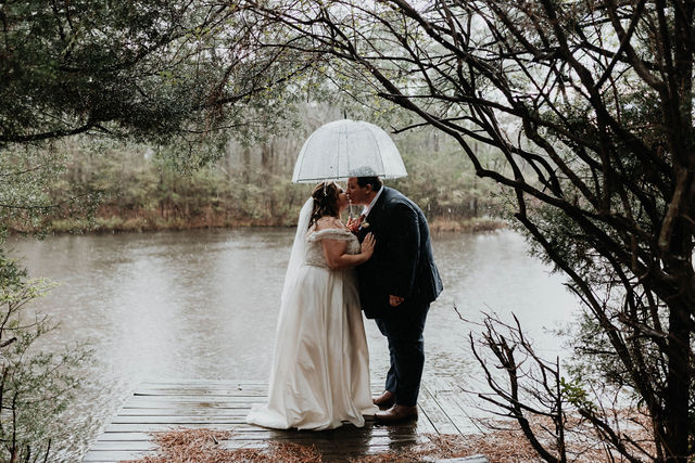Bride and groom kissing under an umbrella in the rain
