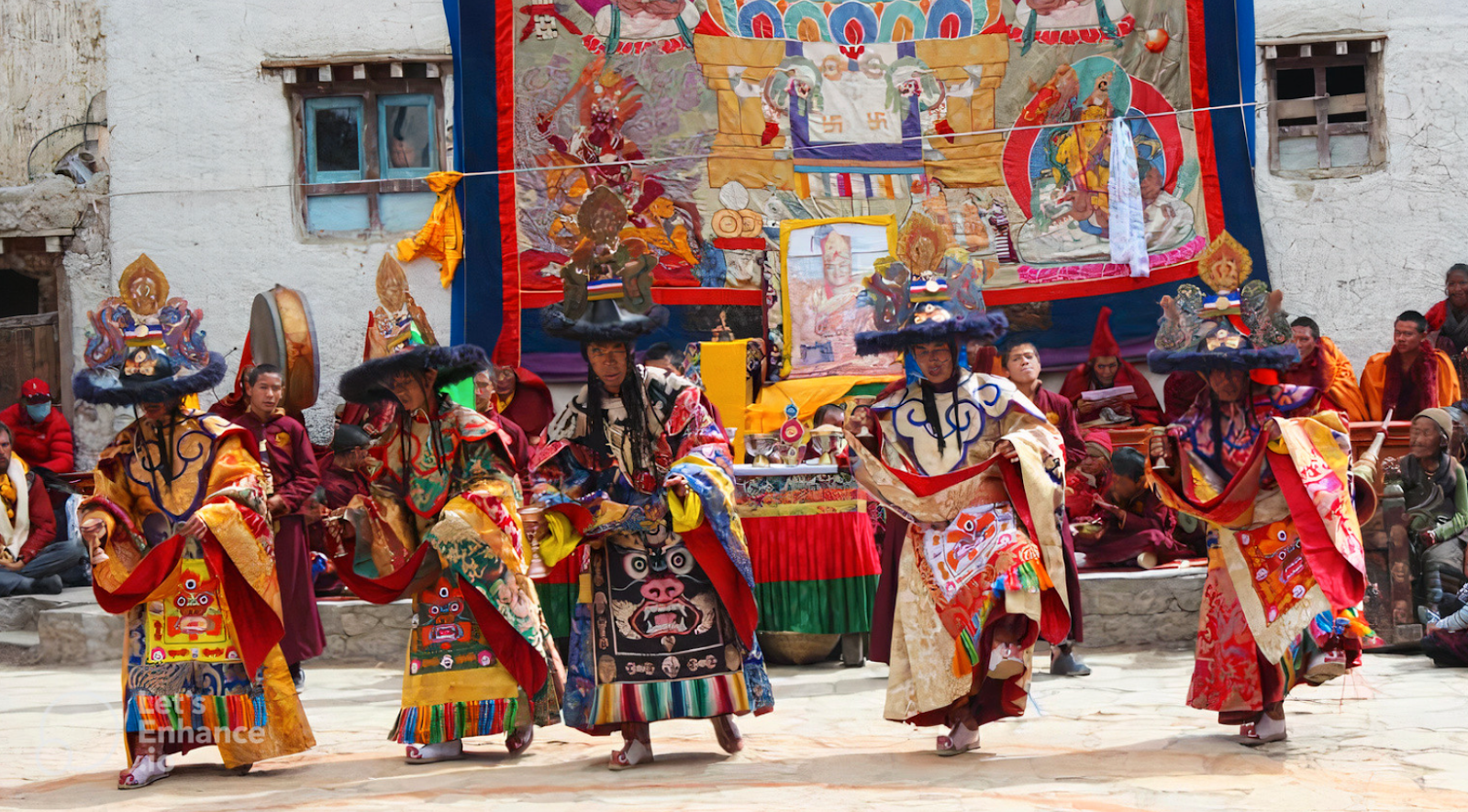 Sherpa dancers in traditional costumes performing a cultural dance during a festival, with colorful banners and a gathering of monks in the background, highlighting the rich Sherpa traditions in the Everest region.