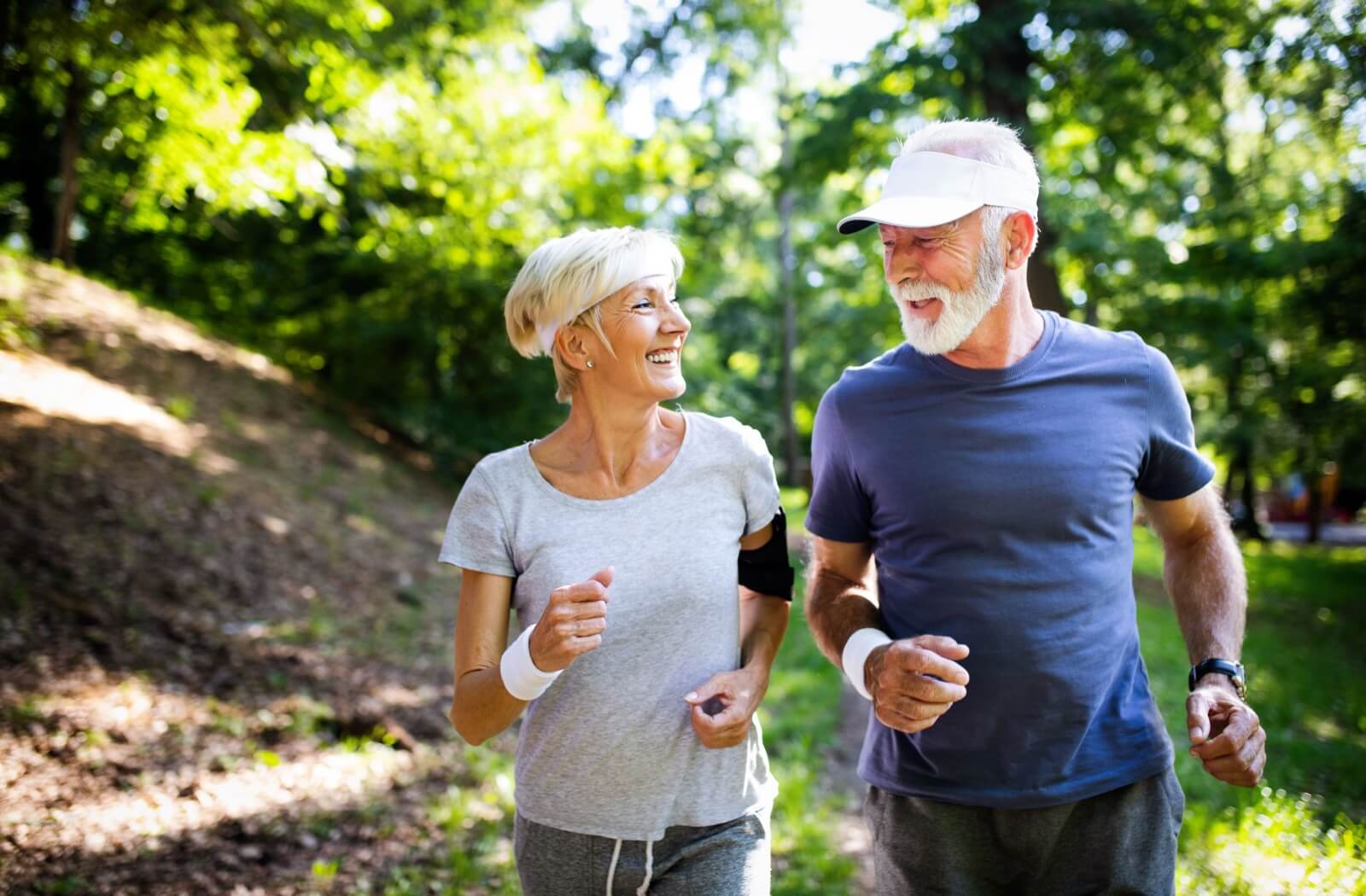 A senior couple happily jogging together outdoors.