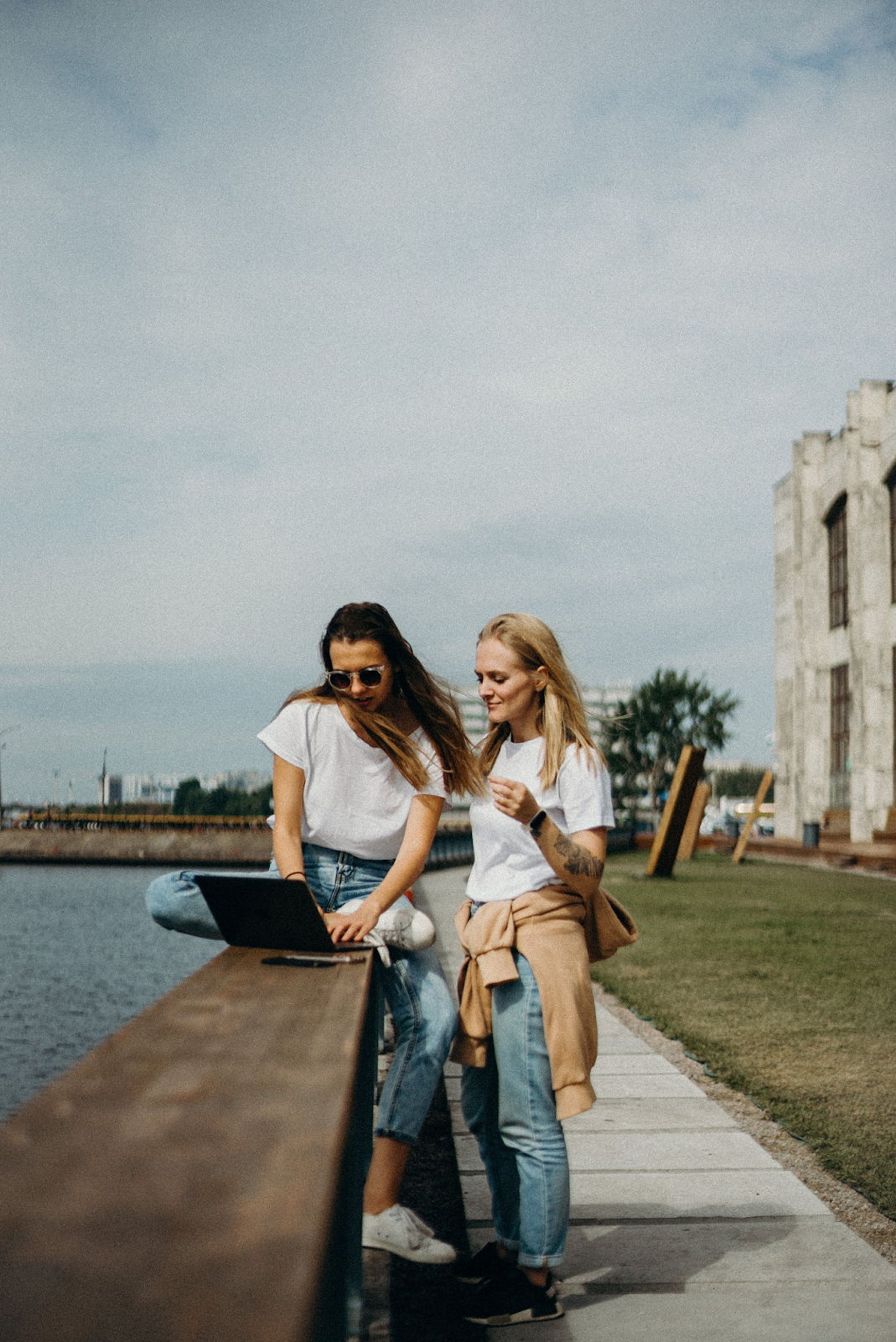 Two Girls on Riverside Viewing Something on Laptop