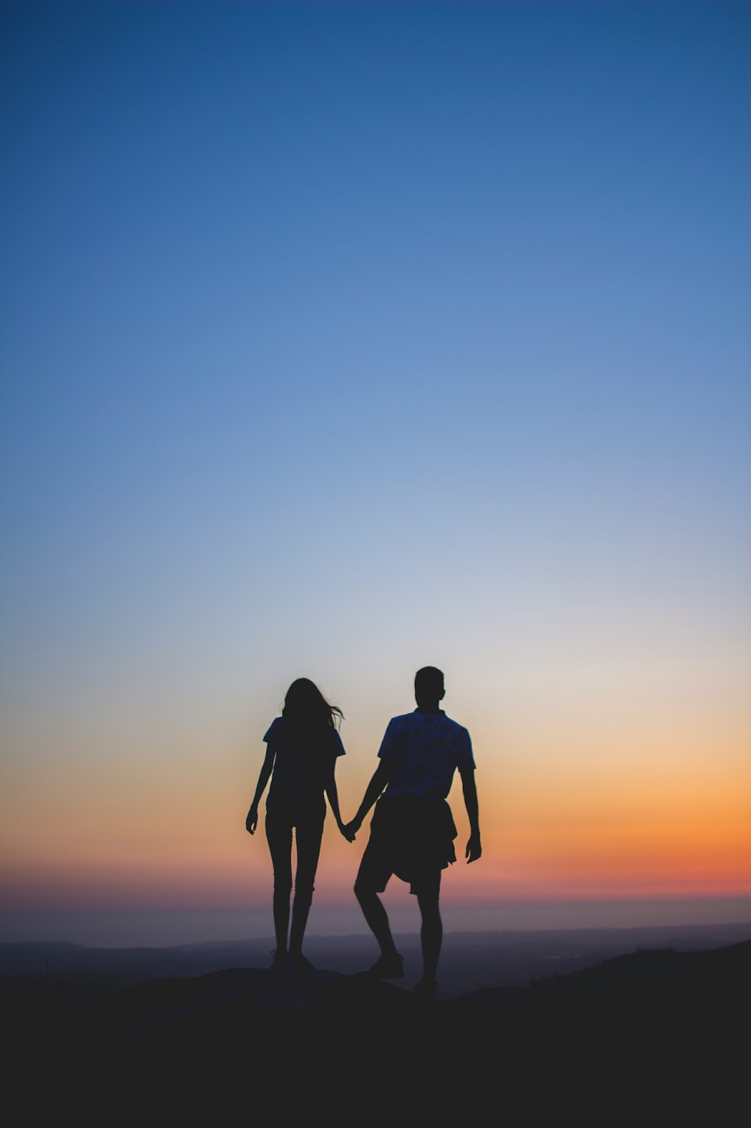 A couple enjoying hiking watching the sunset over the mountains. 