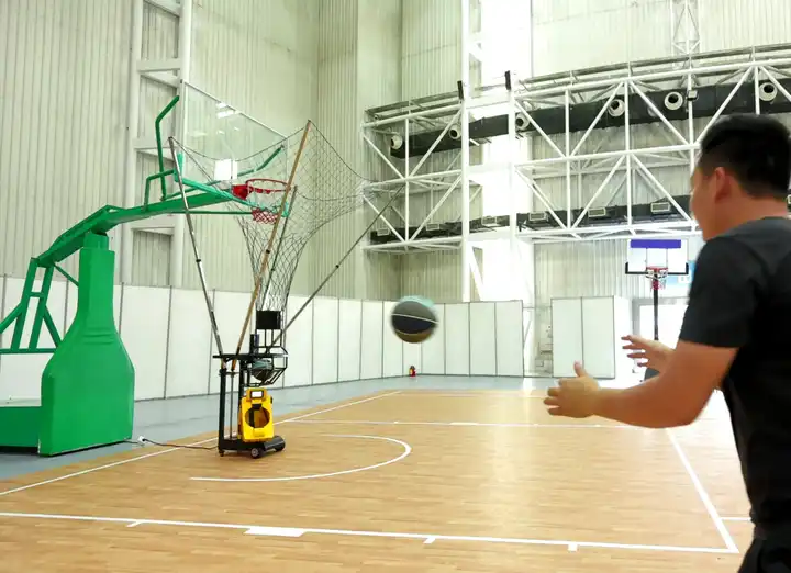 A man training using a basketball shooting machine in an empty court