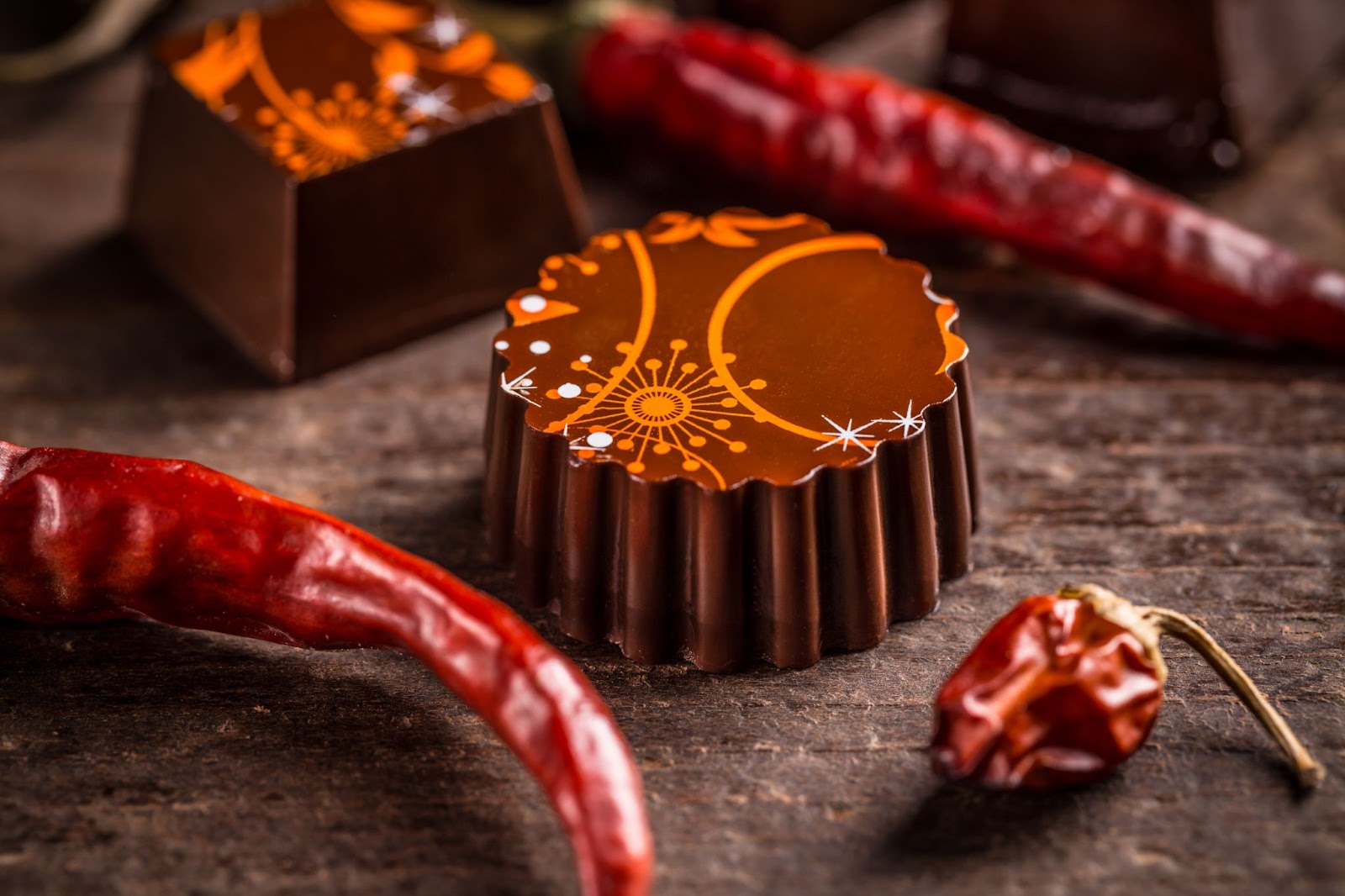 Chili-infused Mexican truffle chocolates surrounded by vibrant red chili peppers, highlighting the spicy essence infused in