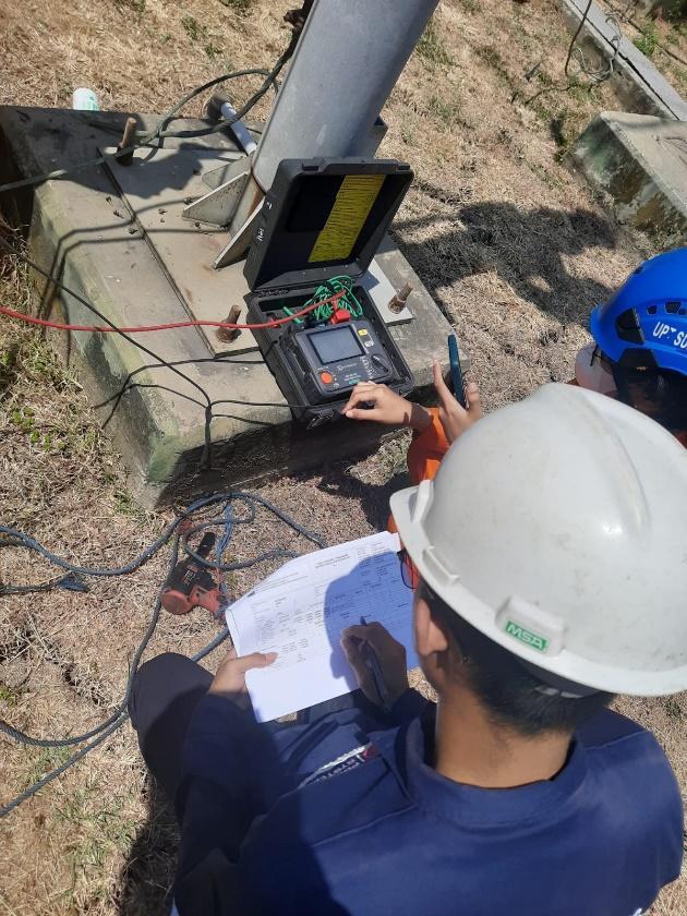 A group of men in hardhats looking at a device

Description automatically generated