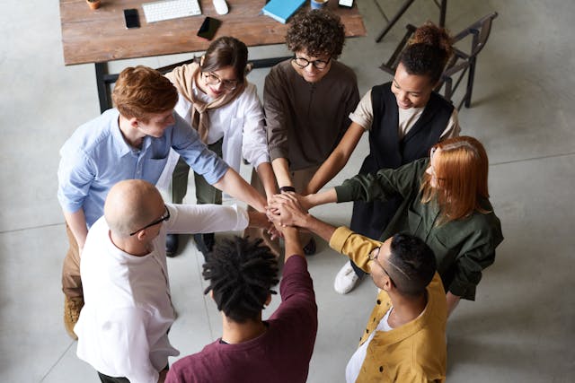 A diverse group of individuals standing and stacking their hands together in a sign of unity and teamwork