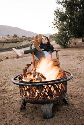 A person sitting in a chair by a fire pit

Description automatically generated