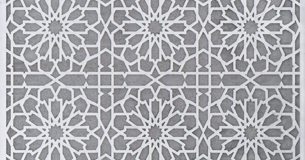 Intricate white flower pattern on a gray wall.