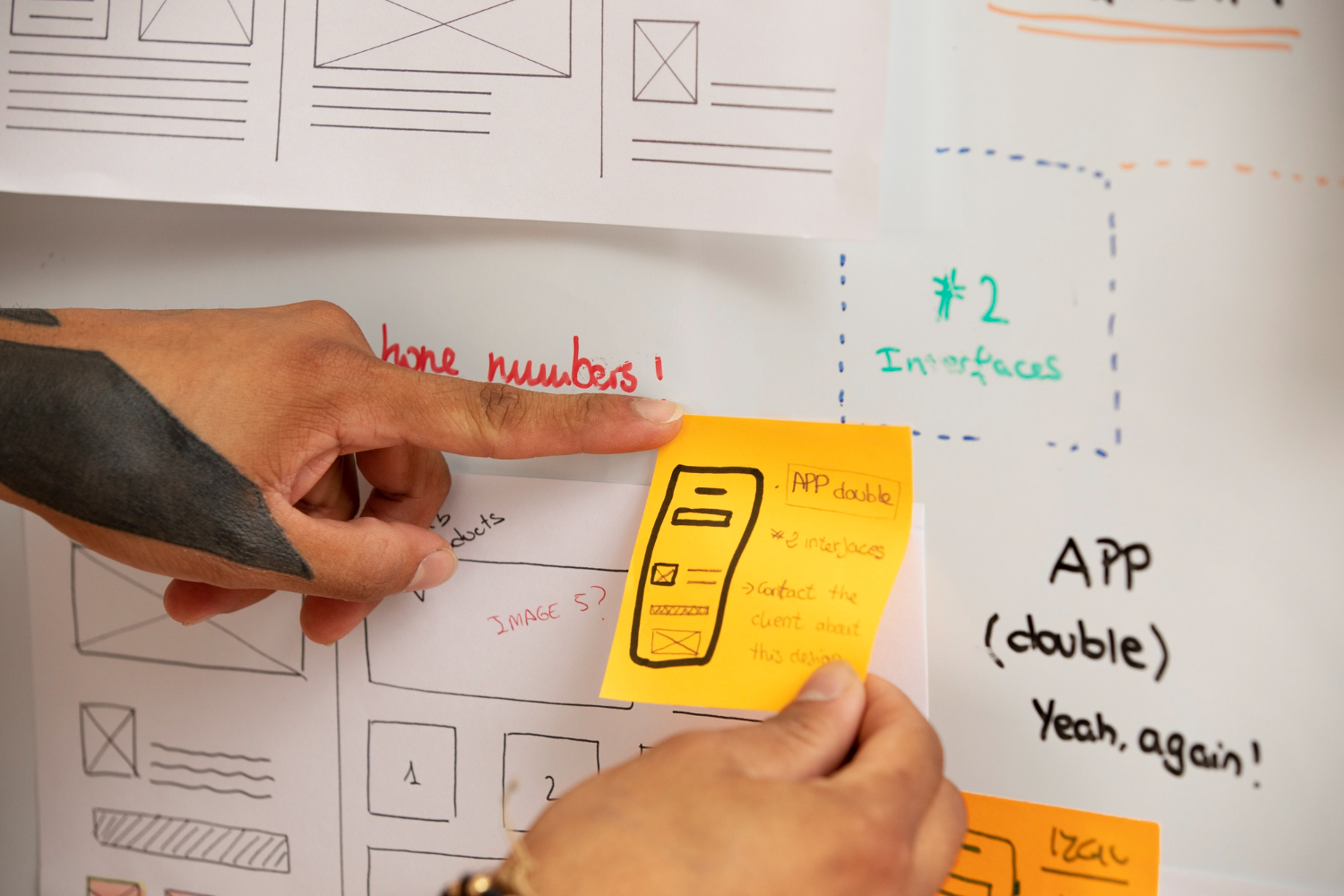person placing a sticky note on a white board with an app strategy