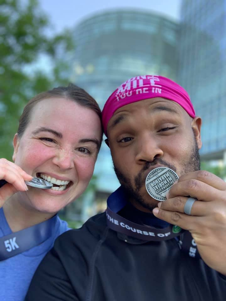 John and wife kissing their marathon medals.