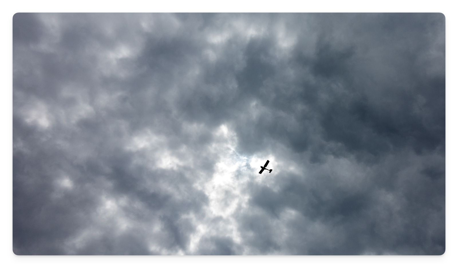 An airplane flying under overcast clouds.