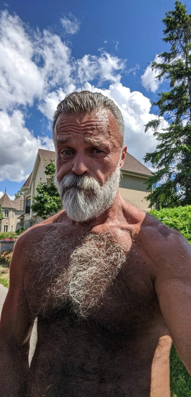 Daddy John gay onlyfans content creator shirtless outside taking a selfie showing off his hairy chest