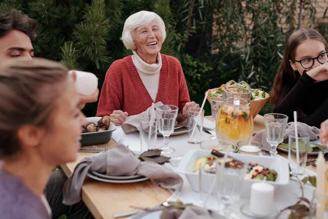 elderly woman laughing with family during a meal