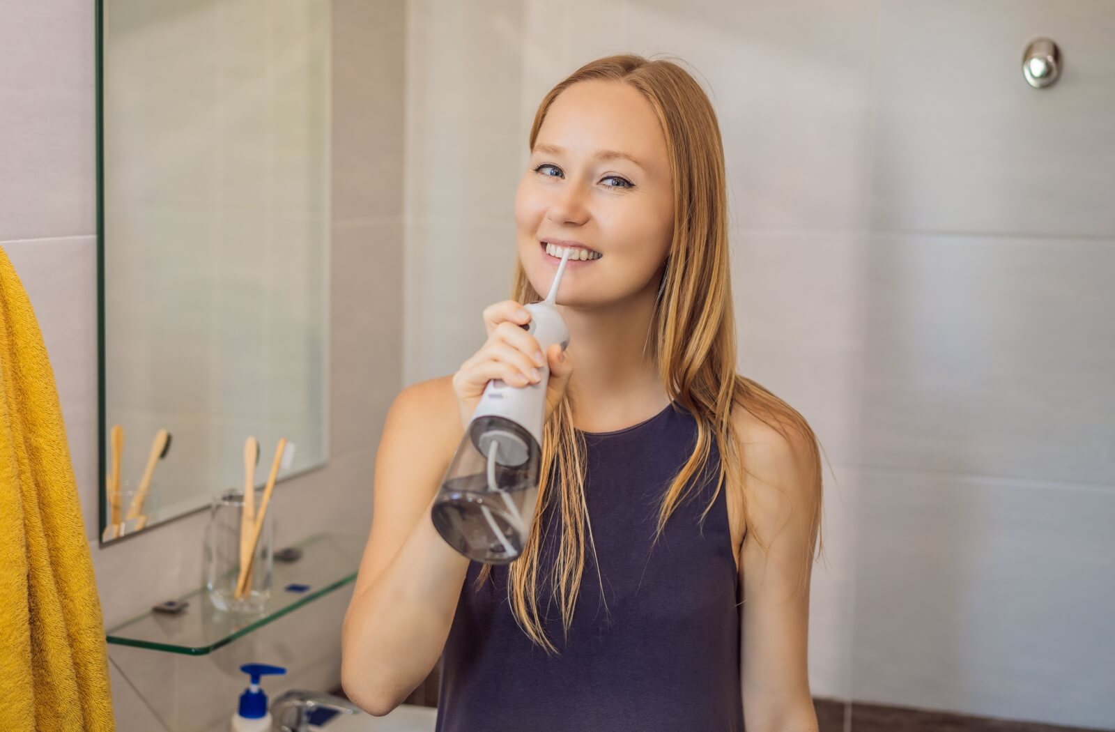 A woman using a water floss as an alternative to flossing.