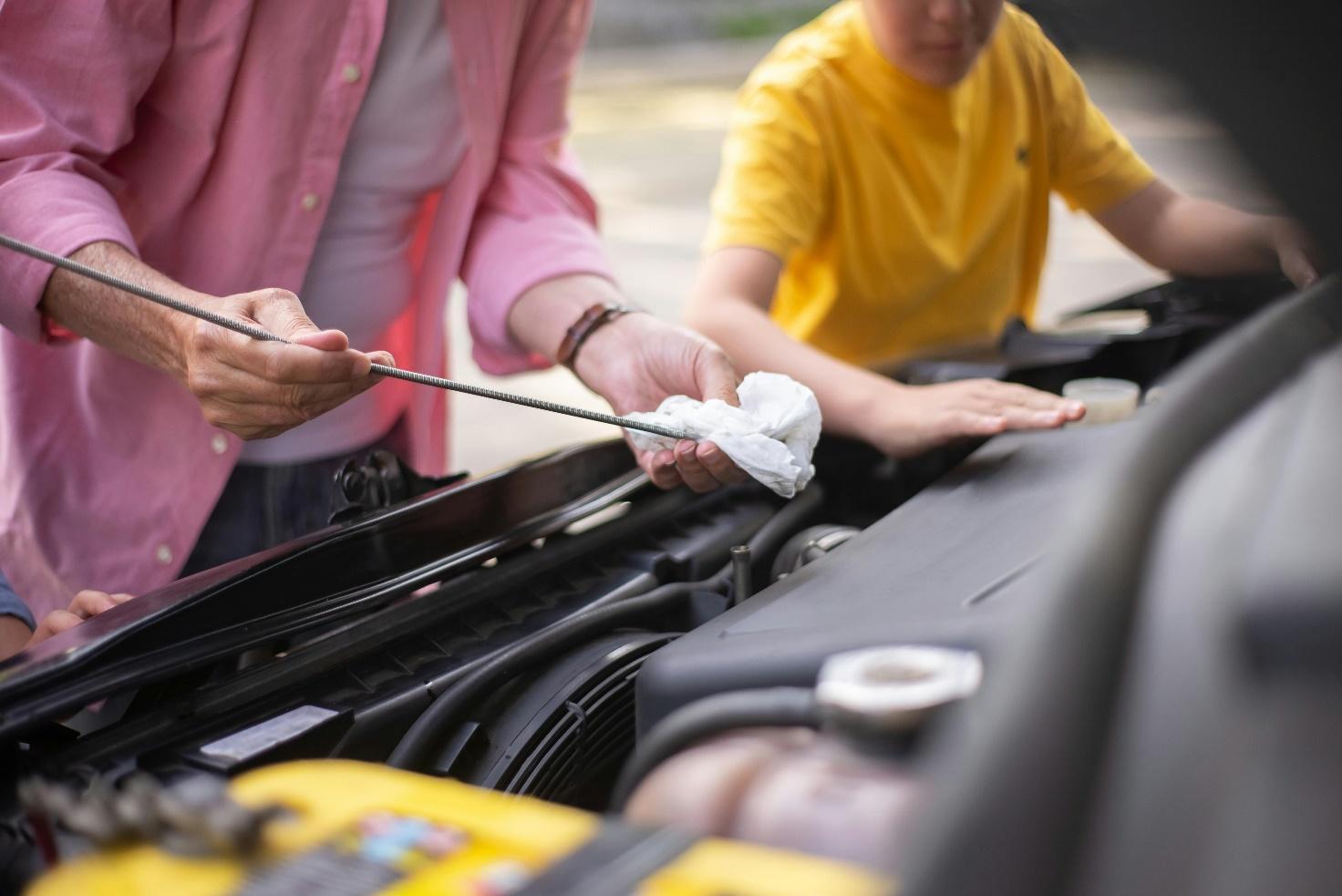 A person and a child checking the engine of a car

Description automatically generated