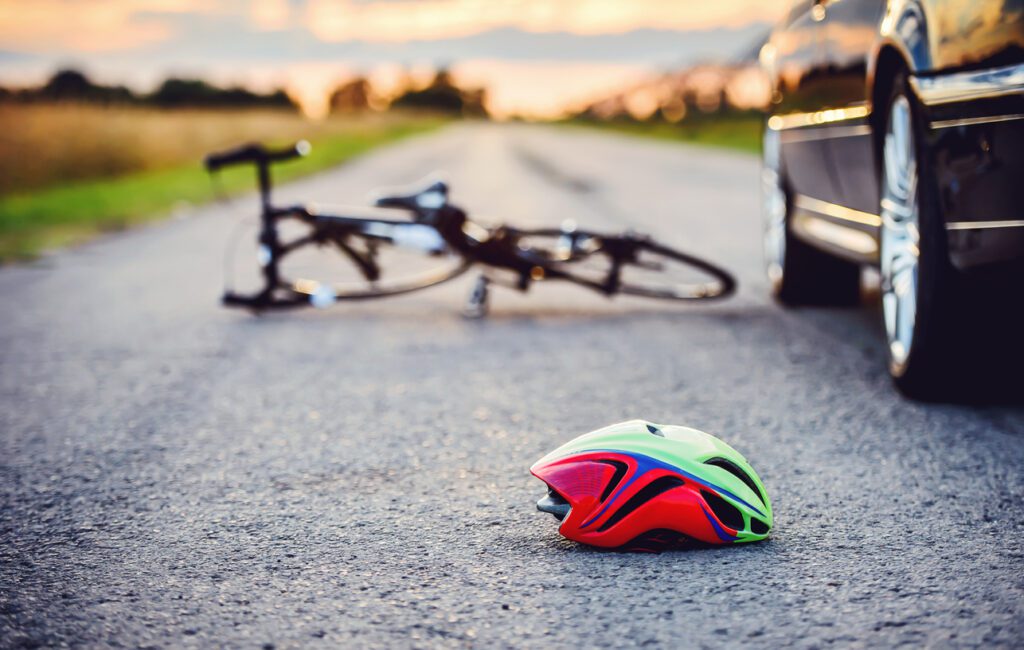 Bicycle and helmet laying in the street next to a car. Our team of Houston-based personal injury lawyers fiercely defend those injured while riding a bicycle. 