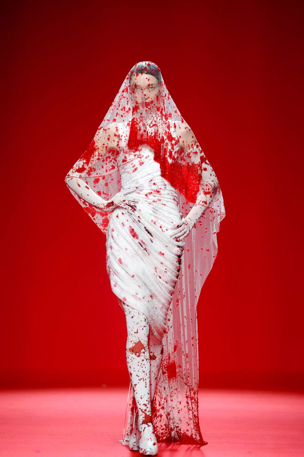 Picture showing  a model in a white gown with veil and covered with blood for the Robert Wun show