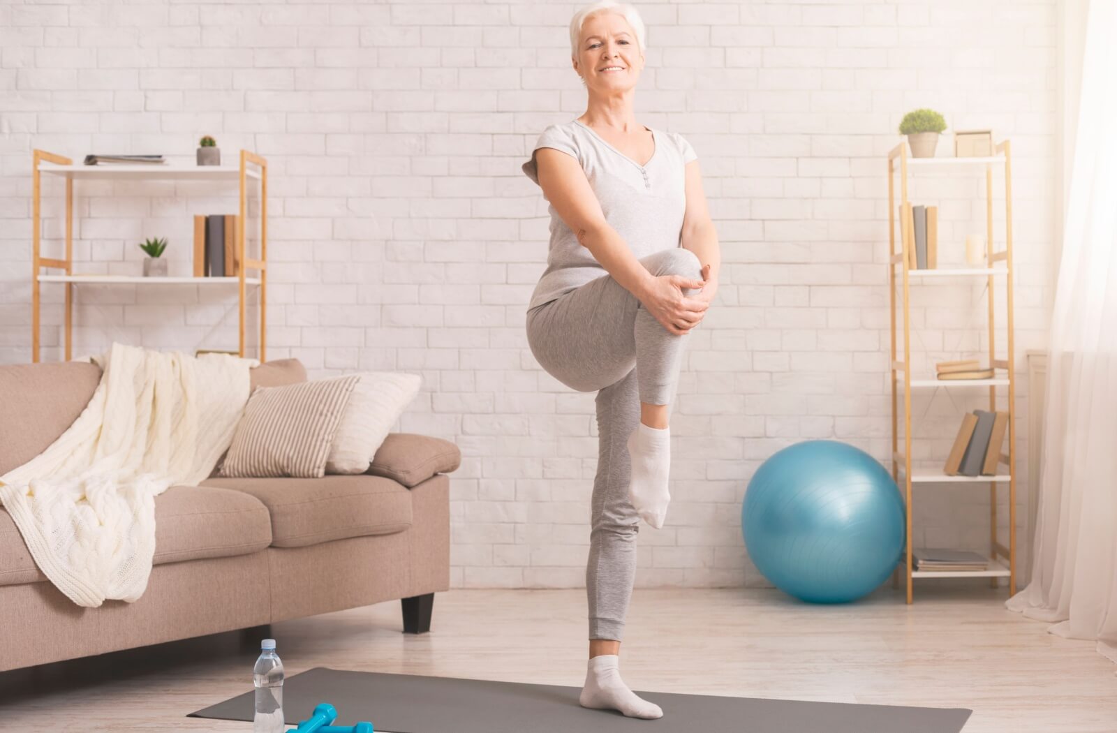 An older adult woman standing on one leg to improve her balance.