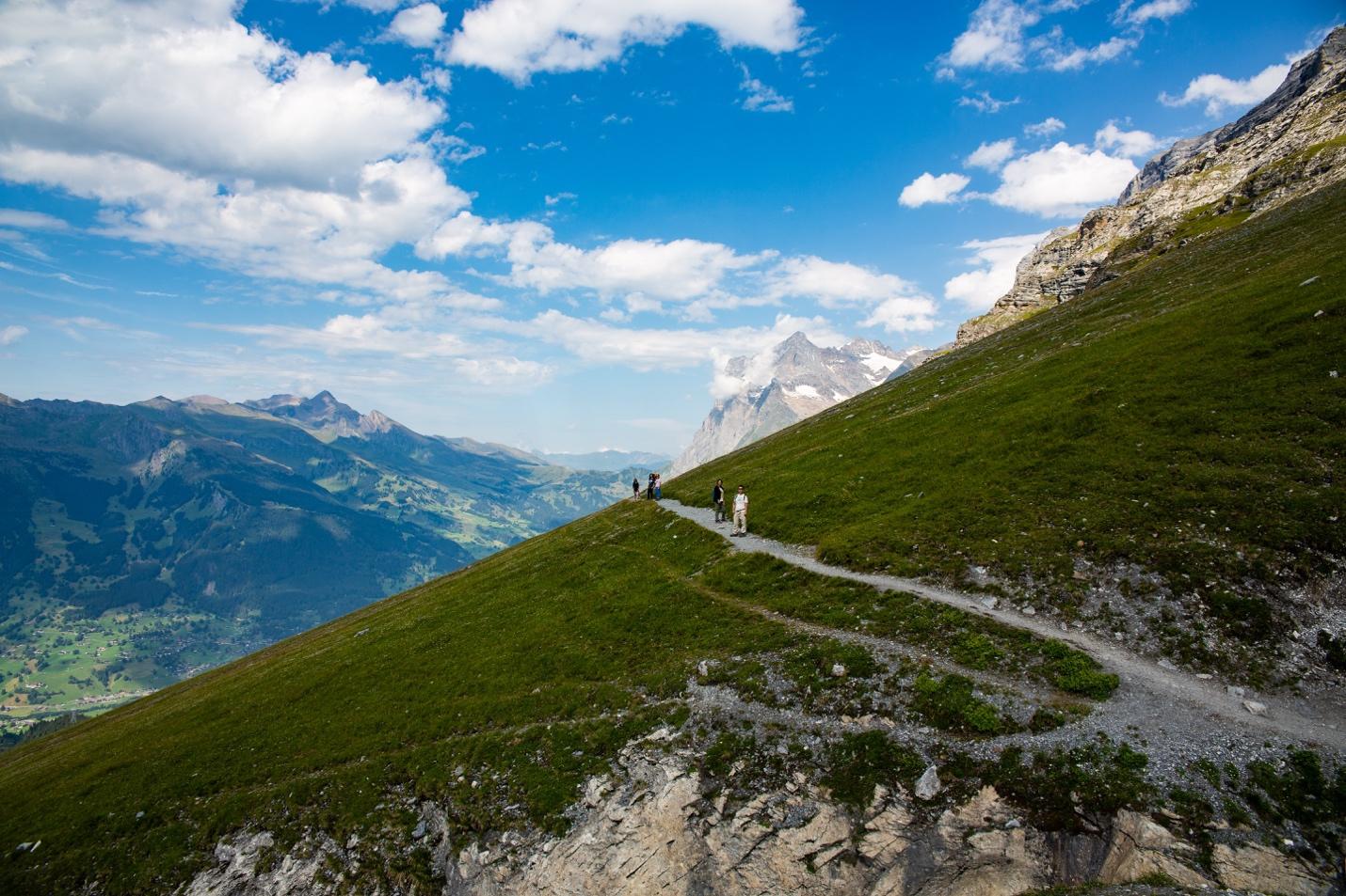 A group of people walking on a path on a mountain

Description automatically generated