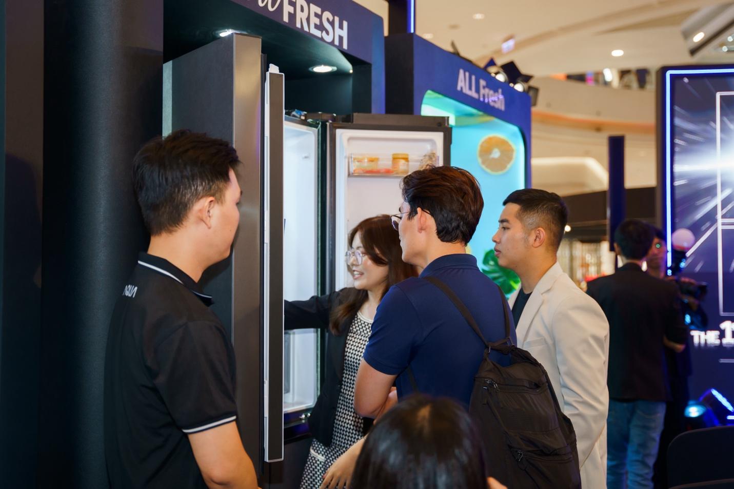 A group of people standing around a refrigerator

Description automatically generated