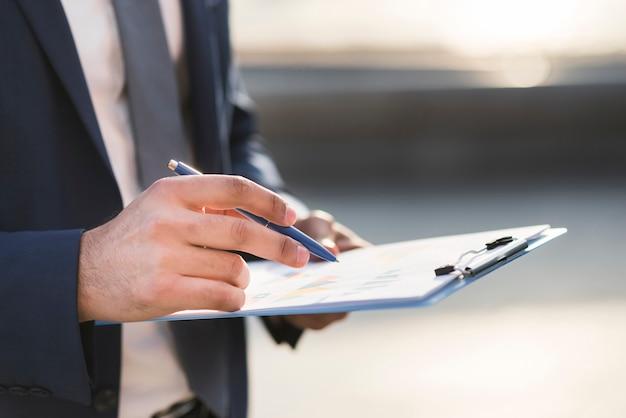 Close-up photo of a business man checking clipboard