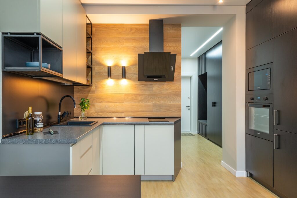 Interior of contemporary kitchen with counter under shelves and cabinets with microwave and oven with hood